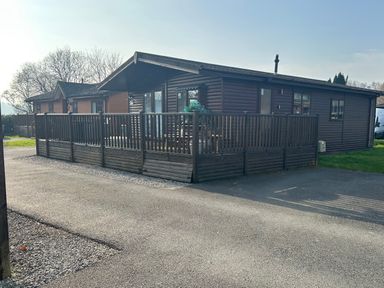 A log cabin with decking on a driveway at Lake View Lodge, Lakeside 3, White Cross Bay, Windermere