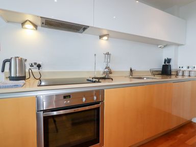 A kitchen counter with a kettle stove oven sink and utensils at Fistral Pearl in Newquay