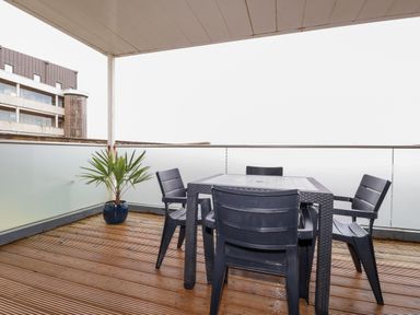 A covered balcony with a table and four chairs and a potted plant at Fistral Pearl in Newquay