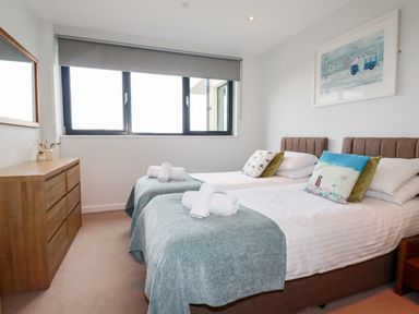 A bedroom with two single beds a wooden dresser and a window at Fistral Pearl in Newquay