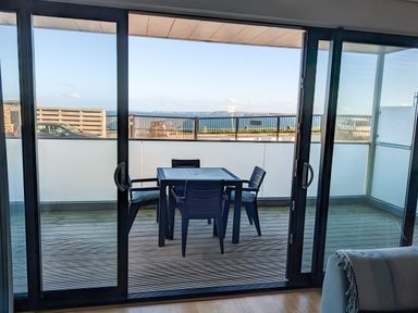 A balcony with a table and four chairs overlooking the sea at Fistral Pearl in Newquay