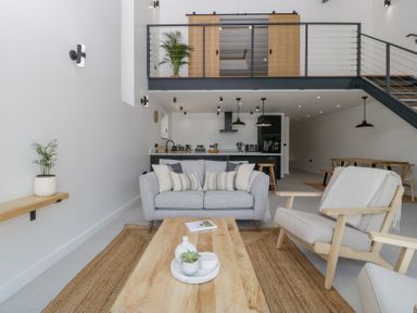 A living room with a gray sofa two armchairs and a wooden coffee table with plants and a book at Basswood Barn in Lime Tree Barn