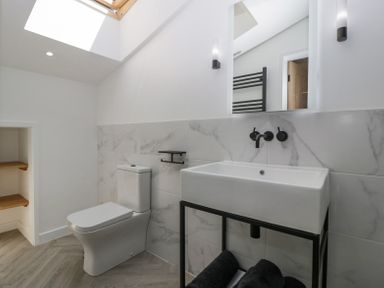 A bathroom with a toilet sink and mirror under a skylight at Basswood Barn in Lime Tree Barn