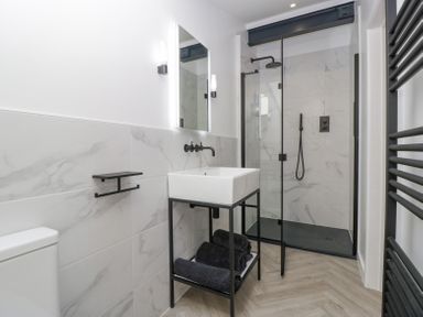 A bathroom with a sink, mirror, towel rack, and walk-in shower at Basswood Barn in Lime Tree Barn