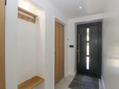 An entryway with a black front door wooden door to a room a wooden coat rack and bench Basswood Barn Lime Tree Barn