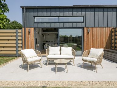 An outdoor seating area with two armchairs a loveseat and a small table on a tiled patio at Basswood Barn in Lime Tree Barn