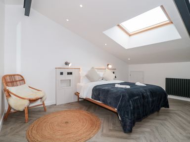 A bedroom with a bed a chair a round rug and a skylight at Basswood Barn in Lime Tree Barn