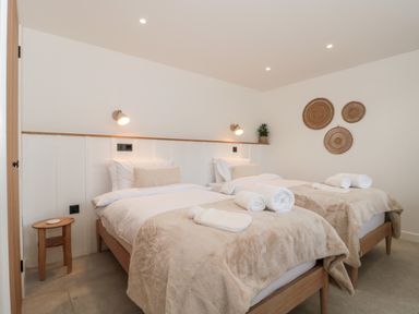 A bedroom with two single beds bedside table and wall decor at Basswood Barn in Lime Tree Barn
