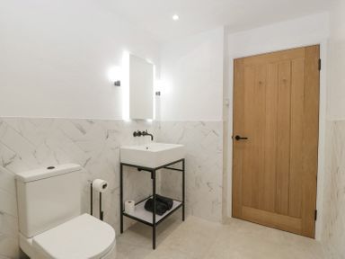 A bathroom with a toilet a sink with a mirror and a wooden door at Linden Barn in Wincanton