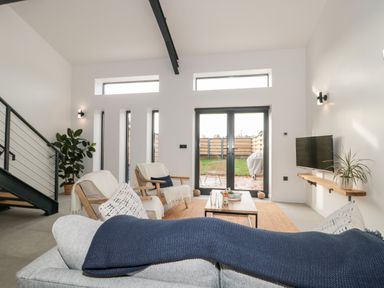 A living room with sofa and chairs facing a coffee table and tv at Linden Barn in Wincanton