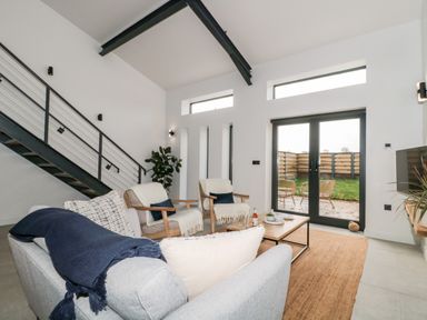 A living room with a sofa two armchairs a coffee table and stairs at Linden Barn in Wincanton