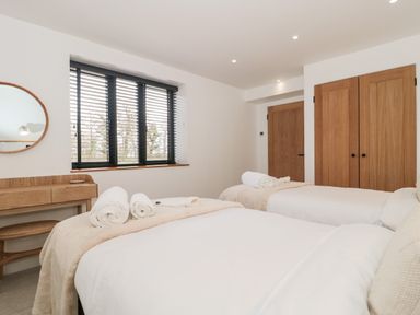 A bedroom with two single beds white linens wooden desk and round mirror at Linden Barn Wincanton