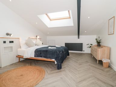 A bedroom with a double bed under a skylight a wooden dresser a round rug and a black radiator at Linden Barn in Wincanton