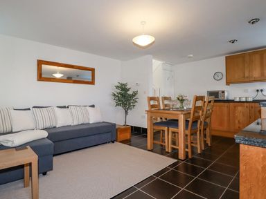 An open plan living and dining area with a sofa and dining table at The Mill in Trethevy near Tintagel