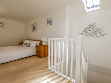 A bedroom with a bed two bedside tables lamps and a stair railing at The Mill in Trethevy near Tintagel
