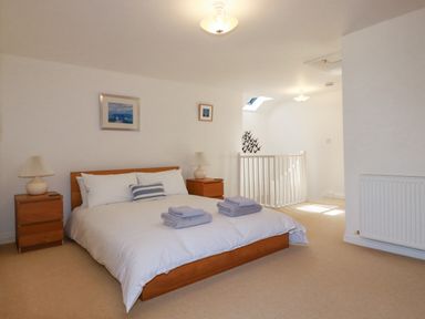 A bedroom with a bed bedside tables lamps and framed pictures on wall at The Mill in Trethevy near Tintagel
