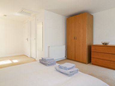 A bedroom with towels on a bed a wooden wardrobe and a wooden chest of drawers at The Mill in Trethevy near Tintagel