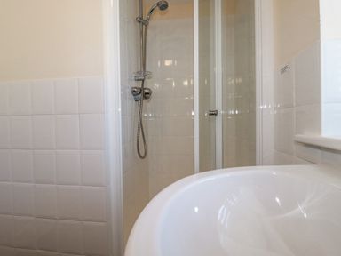 A bathroom shower area with a handheld showerhead and a curved white basin at The Mill in Trethevy near Tintagel