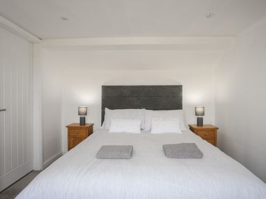 A bedroom with a double bed two bedside tables with lamps and folded towels at Porth Ewyn in Trearddur Bay