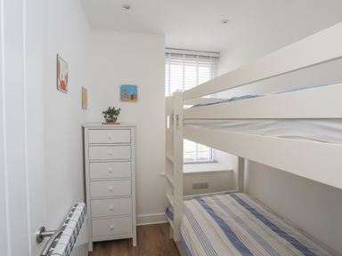 A small bedroom with a white dresser and bunk beds at Golygfa'r Gastell Castle View in Criccieth