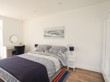 A bedroom with a double bed two bedside tables lamps a desk chair and a wardrobe at Golygfa'r Gastell Castle View in Criccieth