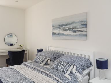 A bedroom with a bed with patterned bedding a desk a round mirror and a lamp at Golygfa'r Gastell Castle View in Criccieth