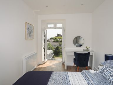 A bedroom with a bed a desk a chair and an open door showing a castle view at Golygfa'r Gastell Castle View in Criccieth