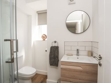 A bathroom with a toilet shower sink and round mirror at Golygfa'r Gastell Castle View in Criccieth