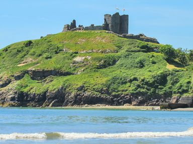 A ruined castle on a grassy hill by the sea at Golygfa'r Gastell Castle View in Criccieth