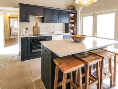 A kitchen with a countertop island and wooden stools at The Courtyard in Kirklinton near Longtown