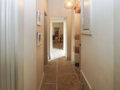 A narrow hallway with stone floor tiles leading to a room with a dining table and chairs at The Courtyard in Kirklinton near Longtown