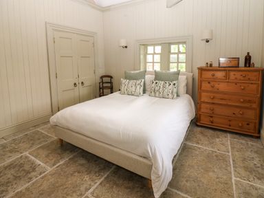 A bedroom with a double bed wooden chest of drawers and a chair at The Courtyard in Kirklinton near Longtown