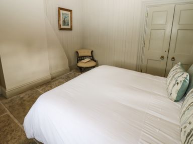 A bedroom with a bed with pillows chairs and a framed picture on the wall at The Courtyard in Kirklinton near Longtown
