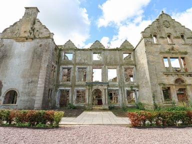 A stone building ruin with missing windows and a stone path in front at The Courtyard in Kirklinton near Longtown