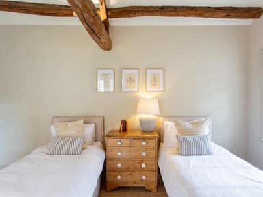 A bedroom with two single beds a wooden dresser and framed pictures on the wall at The Courtyard in Kirklinton near Longtown