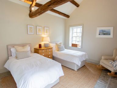 A bedroom with two single beds a wooden chest of drawers and a rocking chair at The Courtyard in Kirklinton near Longtown