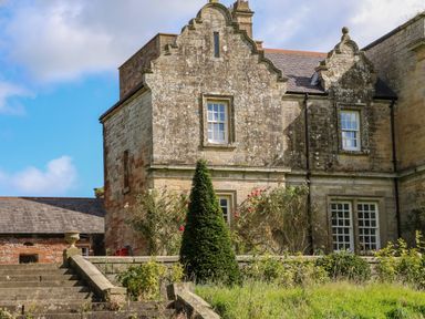 An exterior view of an old stone building with decorative gables surrounded by bushes and steps at The Pavillion in Kirklinton near Longtown