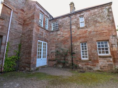 An exterior view of a brick building with white-framed windows and double doors at The Pavillion in Kirklinton near Longtown
