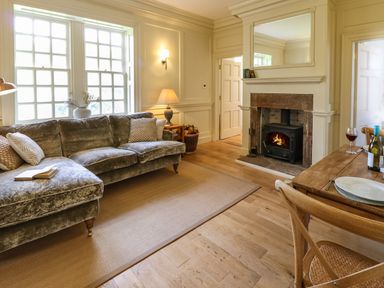 A living room with a velvet sofa a fireplace and a wooden dining table at The Pavillion in Kirklinton near Longtown