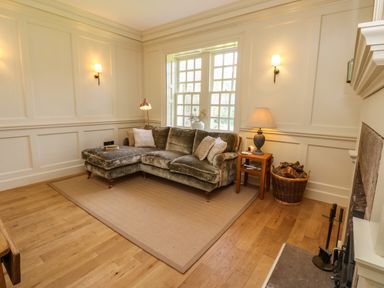 A living room with a sectional sofa and side table by a window at The Pavillion in Kirklinton near Longtown