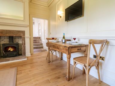 A dining area with a wooden table and chairs a fireplace and a wall-mounted TV at The Pavillion in Kirklinton near Longtown