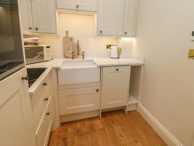 A kitchen corner with a white sink wooden chopping boards a microwave kettle and white cabinets at The Pavillion Kirklinton near Longtown