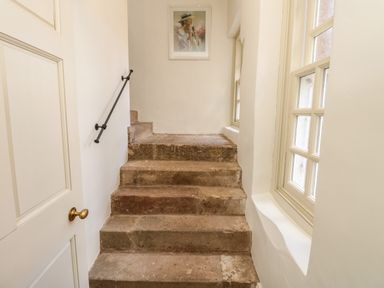 A stone staircase with a handrail on the left wall and windows on the right at The Pavillion in Kirklinton near Longtown