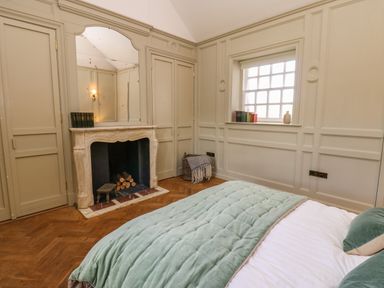 A bedroom with a bed green blanket fireplace mirror and window at The Pavillion in Kirklinton near Longtown