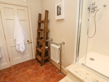 A bathroom with a wooden shelving unit radiator and a glass-enclosed shower at The Pavillion Kirklinton near Longtown