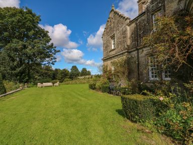 A garden with lawn chairs and a small table set near a stone building at The Pavillion in Kirklinton near Longtown
