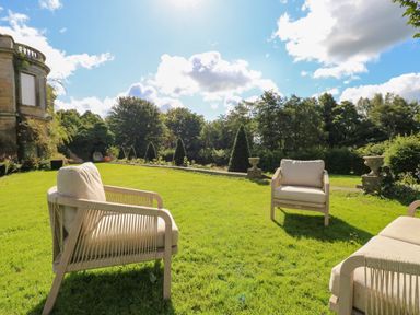 An outdoor garden area with cushioned chairs on grass at The Pavillion in Kirklinton near Longtown