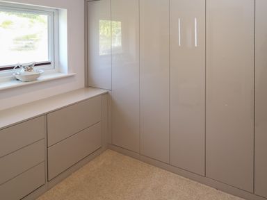 A room with built-in cabinets and drawers under a window with a ceramic jug on the windowsill at Greenside Studio in Praa Sands