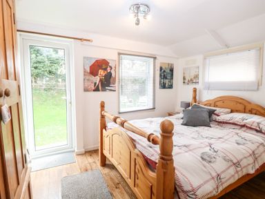 A bedroom with a wooden bed and wardrobe with paintings on the walls at Suzannes Beach Hut in Bacton near Walcott