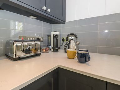 A kitchen countertop with a toaster kettle coffee machine three mugs and a glass bowl at Hawthorn Croft in Haverthwaite